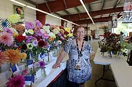 Woman standing near vases with flowers.