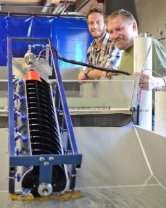 PNNL’s Sam Harding and Percheron Power’s Jerry Straalsund (in foreground) conduct a mini turbine test. The early trials allow the team to try out blade designs and orientations in a water test rig before scaling up to larger sizes. 