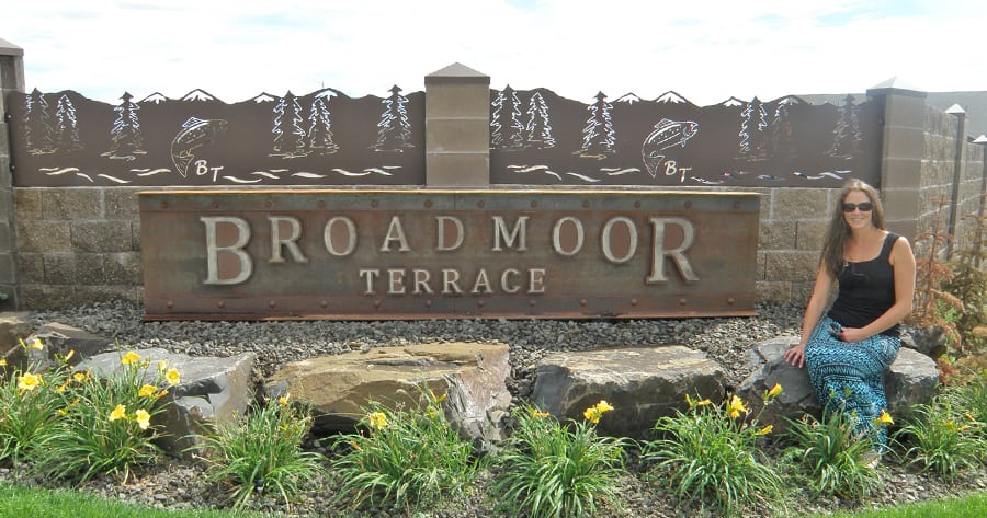 Property Manager Wendy Greeno of D&R Investments in Pasco sits in front of the custom-designed metal sign of the new Pasco subdivision, Broadmoor Terrace, located just east of the Broadmoor Outlet mall. 