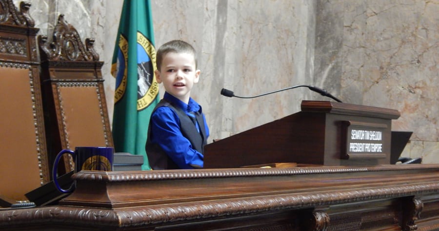 Luke Lynch, 7, of Moses Lake, plays Feb. 24 at the podium of the state Senate after a memorial resolution was read honoring his father, Kyle Lynch, who died of cancer in November. Kyle Lynch was an aide for two 13th District senators from 2003-16. (Courtesy Rebecca White of Columbia Basin Herald)
