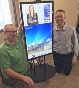 Abadan Tri-Cities’ Josh Smith, left, solutions analyst, and Tyler Best, president/general manager, pose next to virtual receptionist ALICE. Abadan is selling the new technology to area businesses.