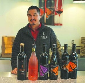 Victor Palencia shows his selection of Monarcha and Palencia wines from behind the counter of his new tasting room at the Columbia Gardens Wine and Artisan Village on Columbia Drive in Kennewick. Palencia plans to open his doors in February.