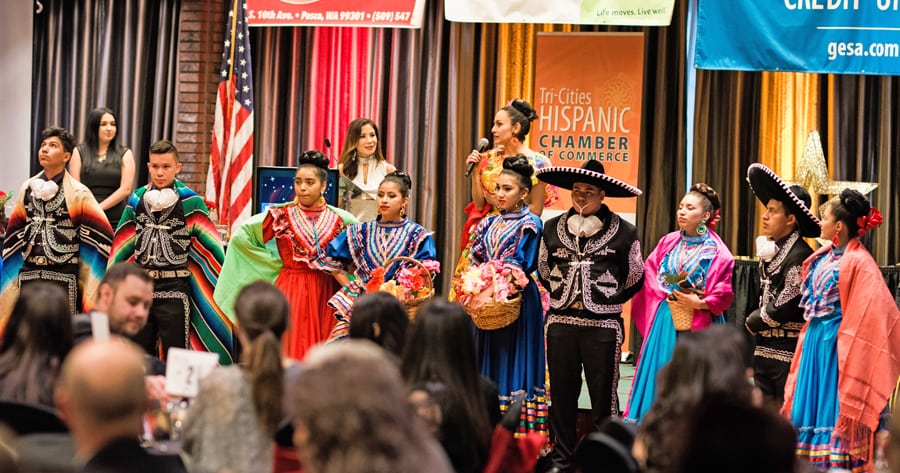 Roxana Romero of Kalliflorico Dance introduces the group during the Tri-Cities Hispanic Chamber of Commerce’s 2018 Una Noche de Éxitos, or A Night of Achievements, gala dinner in April that recognized those who work to make the community a better place to live. Chamber President Nikki Torres is pictured behind the podium and chamber board member Sayuri Peralta is at far left. (Courtesy Tri-Cities Hispanic Chamber of Commerce)