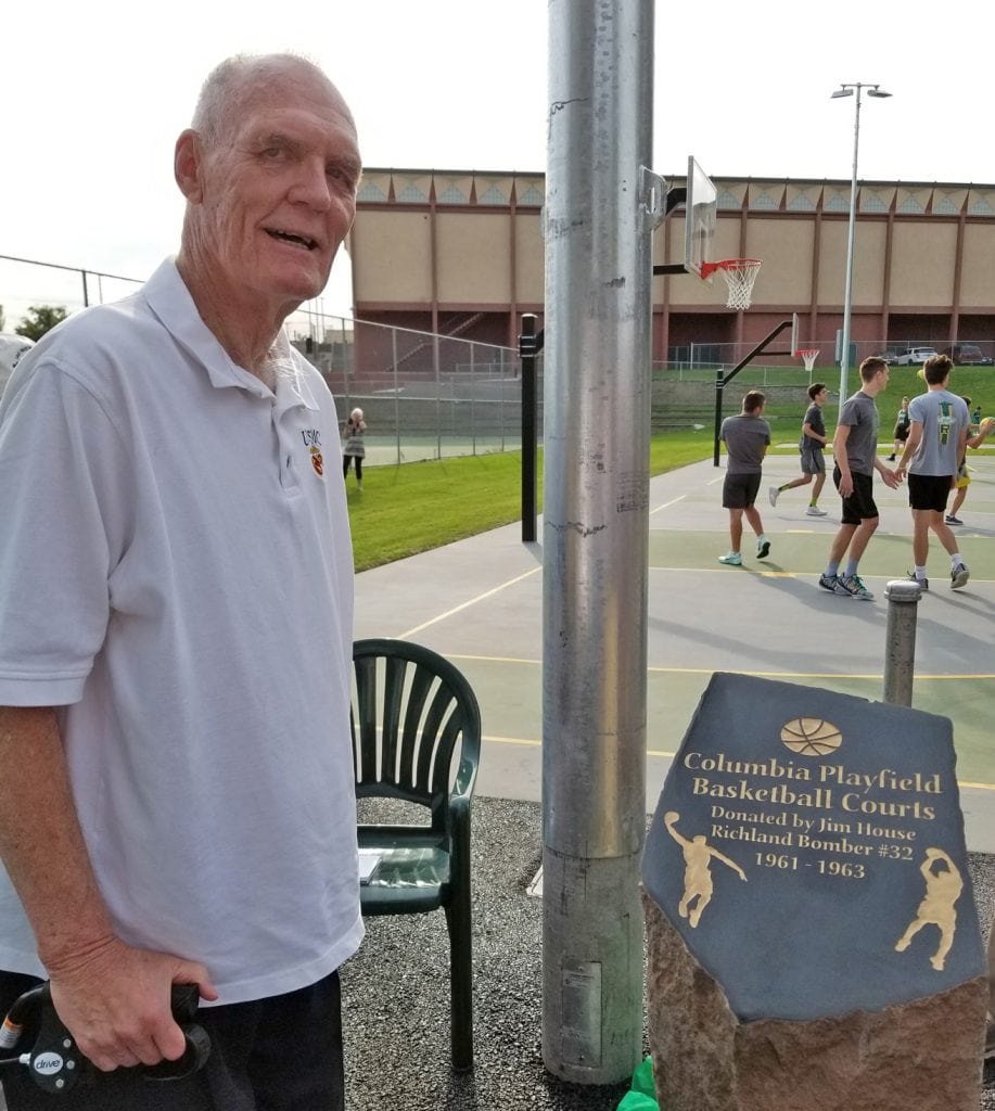 Jim House, a 1963 graduate of Richland High School, stands next to the rock that honors him for helping replace the basketball courts at Columbia Playfield in Richland. The courts can be seen in the background.