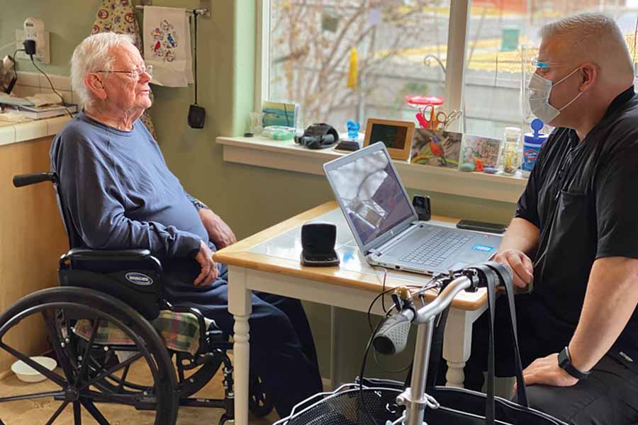 George Perkins, left, chats with his audiologist, Neil Aiello, at his Kennewick home. The 83-year-old was the first patient to use Columbia Basin Hearing Center’s new mobile clinic, called Hear For You. (Courtesy Columbia Basin Hearing Center)