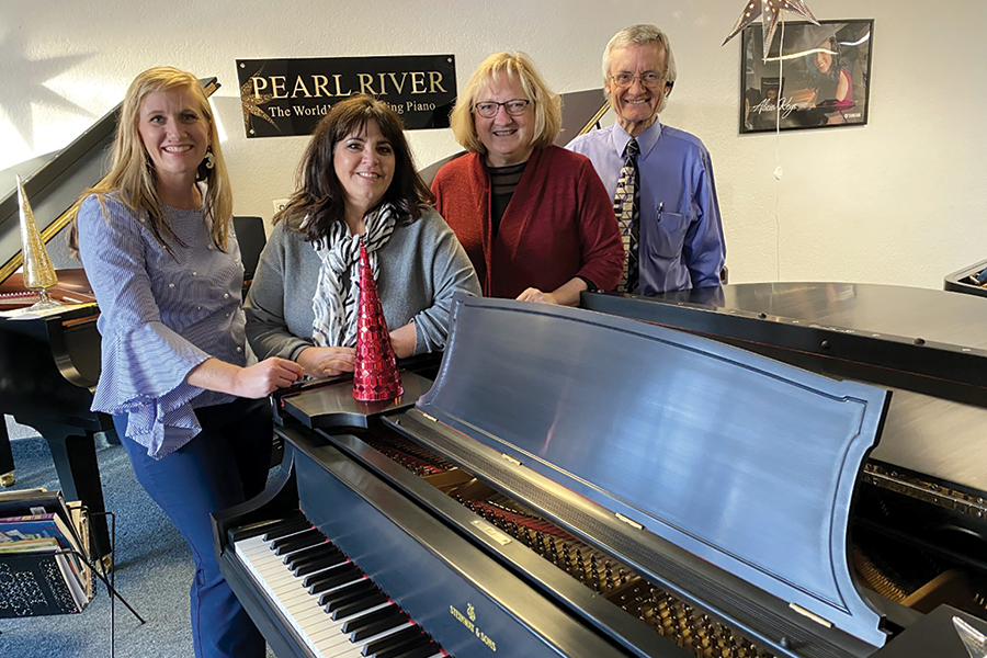 Employees Lydia Dillsworth, from left, and Lisa Ortiz, stand next to Tri-City Music owners Bobbi and Dave Dickerson. The Richland store is a place where people can buy or rent pianos, attend recitals, or listen to concerts to share the joy of music. (Photo by Jeff Morrow)