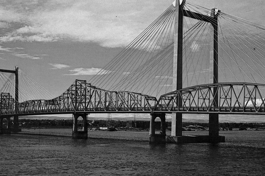 The familiar cable bridge spans the Columbia River beside “old green bridge,” which was torn down in 1990. A single bridge support extending from the water was left near the Kennewick shoreline, leading to the creation of a pier for scenic viewing. (Courtesy East Benton County Historic Society and Museum)