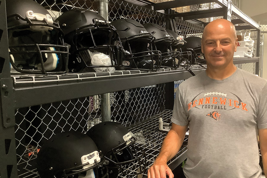 Randy Affholter, head football coach for Kennewick High School, stands next to some of the football helmets he has in stock. (Photo by Jeff Morrow) 