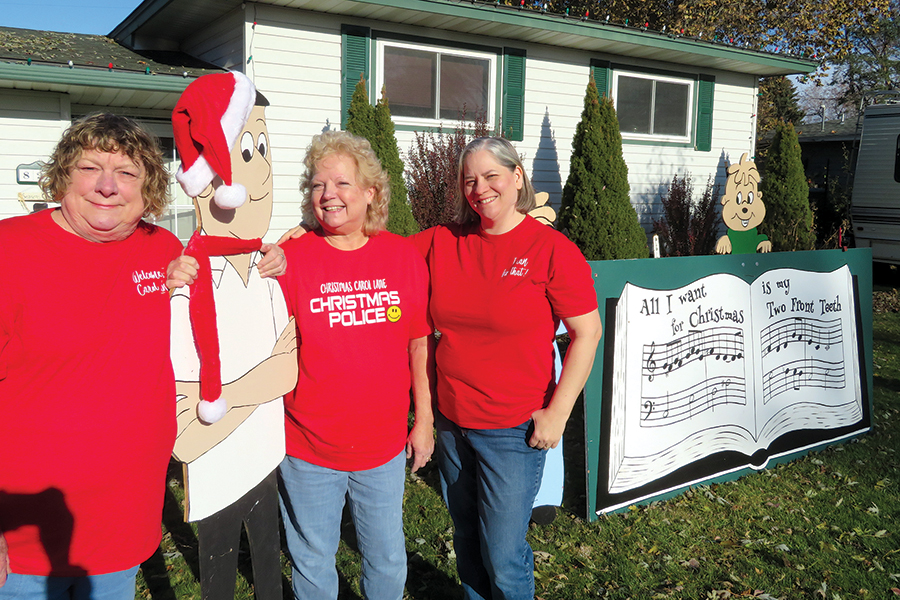 Sandy Nettleton, from left, Debie Britton and Dayna Faultersack are the women who spearheaded the revitalization of Christmas Carol Lane. The south Kennewick subdivision encourages homeowners to display songboards featuring Christmas carols, a tradition dating back to the 1960s. (Photo by Kristina Lord)