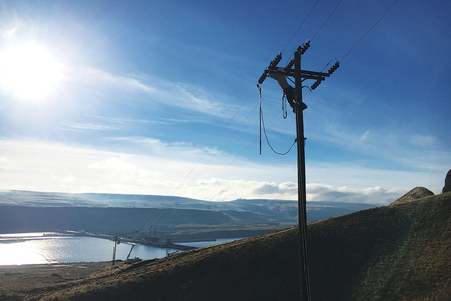 A lineman works on a transmission line above Lower Monumental Dam, which bridges Franklin and Walla Walla counties on the lower Snake River. (Courtesy Franklin PUD)
