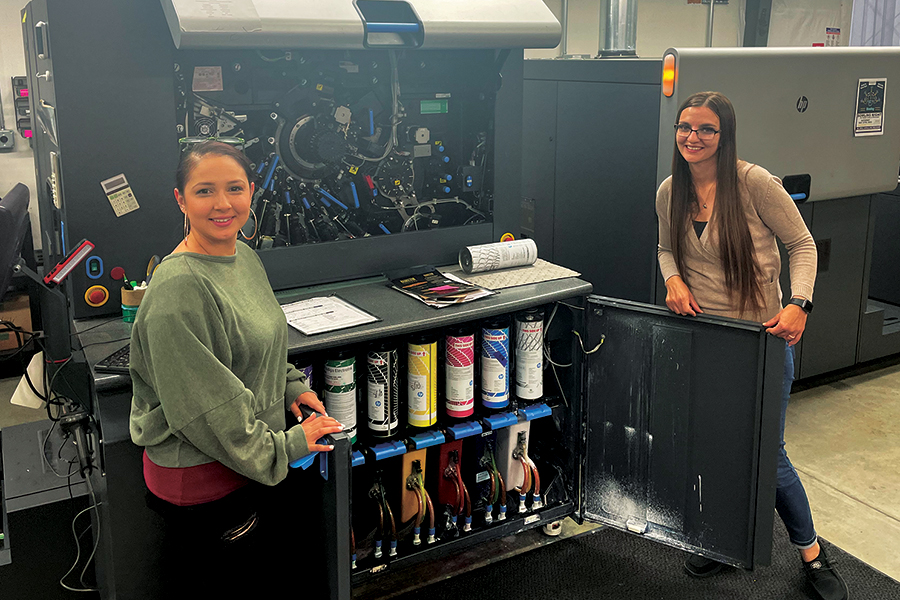 Production manager Lupe Anguiano, left, and Katii Deaton, part owner and general manager of Columbia Label, show off one of the high-tech machines in their production area. (Photo by Robin Wojtanik)